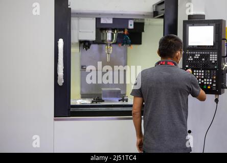 Mechanical technician operating CNC milling machine in workshop. Industrial manufacturing. Stock Photo