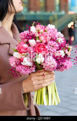 Beautiful young woman holding bridal bouquet in pink lilac tones made of hyacinth, tulips and gypsophila. Stock Photo