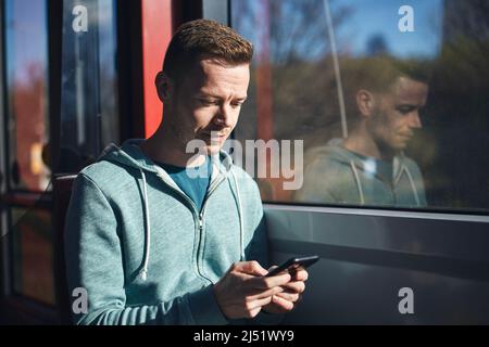 Man using phone while commuting by tram of public transportation. Stock Photo