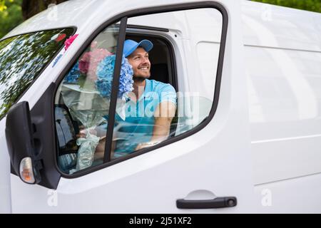 Happy courier inside the white van during flowers delivery is waiting for a client Stock Photo