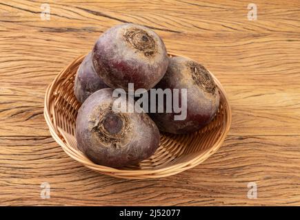 Raw beetroots in a basket over wooden table. Stock Photo