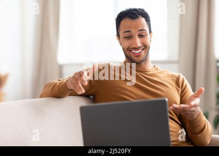 Arab guy making videocall using laptop wearing headphones Stock Photo