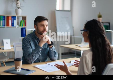 Focused personnel manager and young female job applicant communicarting on work interview at modern company office Stock Photo