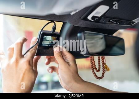 Hand of technician installing front camera car recorder on windscreen car Stock Photo