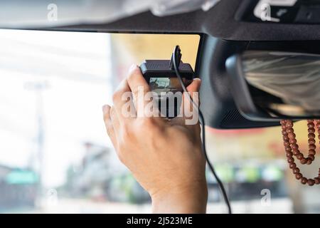 Hand of technician installing front camera car recorder on windscreen car Stock Photo