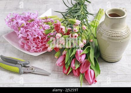 Florist at work: woman shows how to make spring bouquet with tulip, hyacinth and carnation flowers. Step by step, tutorial. Stock Photo