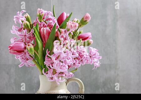 Florist at work: woman shows how to make spring bouquet with tulip, hyacinth and carnation flowers. Step by step, tutorial. Stock Photo