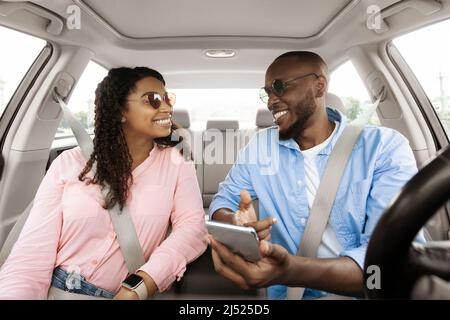 Happy black family driving car and using smartphone Stock Photo