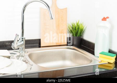 Sink, clean dishes, sponge and dishwashing liquid in the kitchen. Stock Photo