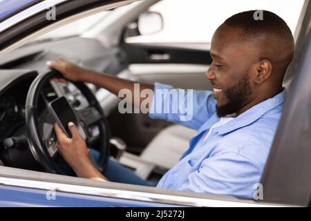 Happy black man using showing smartphone driving car Stock Photo