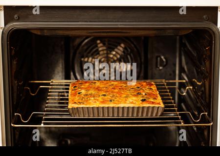 Homemade cheesy Quiche with tomatoes, champignons and olives baked in a home oven. Shallow focus. Stock Photo