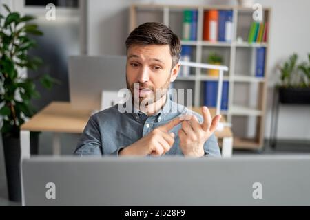 Virtual meeting concept. Portrait of mature business manager having talk using computer at workplace in office Stock Photo