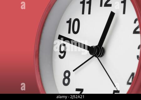 Clock face white with black hands on red background Stock Photo