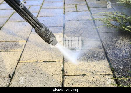 Cleaning dirty paving stones in the garden with a pressure washer. Home worker Stock Photo