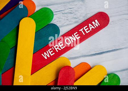 We're one team text on red wooden stick. Teamwork concept Stock Photo