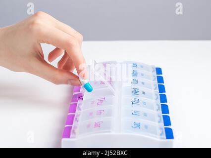 Woman hand taking pill, vitamin from case, holder. Storing scheduled doses of medications in box. Health care and treatment concept. High quality photo Stock Photo