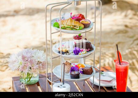 Afternoon tea on tropical sandy beach with shadows from palm trees in summer day Stock Photo