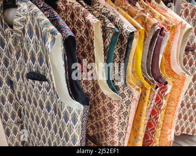 Indian men latest fashion dress hung on hangers, in display in retail shop in market, wedding wear for men India Stock Photo