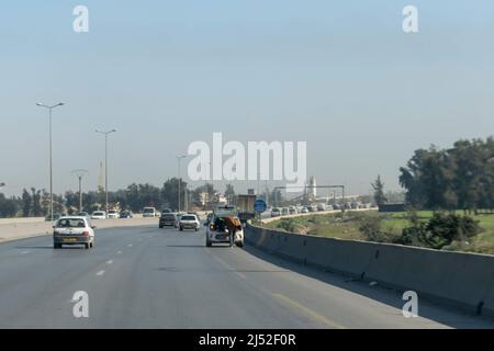 Car parked on the side of the highway turn, a dangerous situation. Stopped on the emergency stop strip speedway, a man is looking inside the car trunk Stock Photo