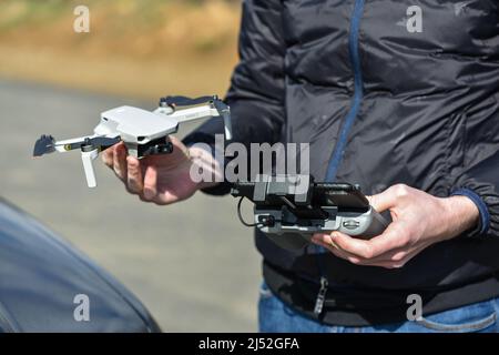 10 April 2022 - Krakow, Poland: Pilot holds the Drone DJI Mavic Mini 2 and DJI remote controller after flight. Stock Photo