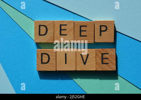 Deep Dive, words in wooden alphabet letters isolated on blue background Stock Photo