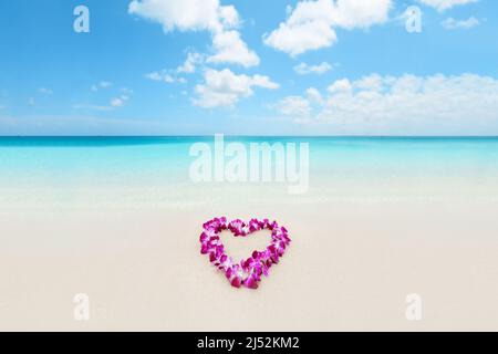 Heart shape lei flowers on perfect white sand beach for Hawaii honeymoon romantic vacation getaway travel. Pink orchids flower necklace lying on Stock Photo