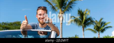Car key new young owner driver man showing keys and thumbs up happy for new convertible buy or sell used cars. Driver's license concept with driving Stock Photo
