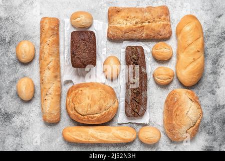 Assortment of fresh bread. Gray concrete background. Bakery products. Top view, flat lay.