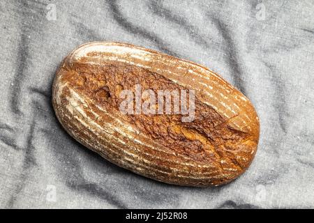 Loaf of bread on gray tablecloth. Top view. Stock Photo