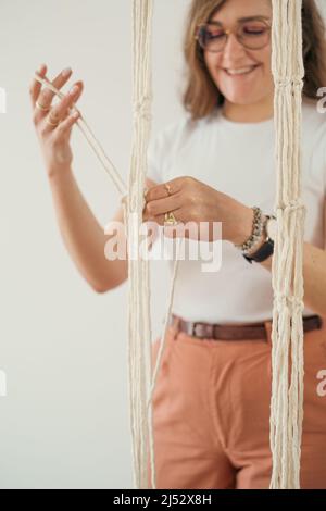 woman weaving macrame flower pot handmade indoors Stock Photo
