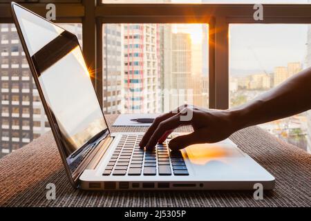 Closeup of hand typing on computer in office with city view Stock Photo