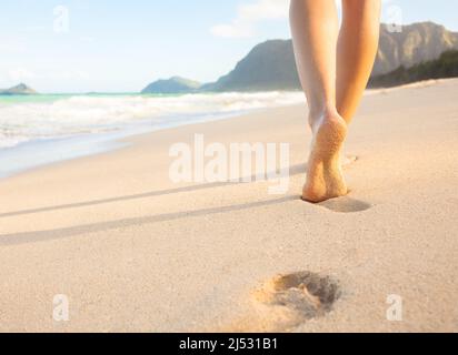 Woman feet walking on beach leaving foot prints in the sand Stock Photo