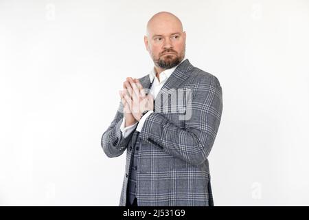 Portrait of serious middle-aged businessman wearing grey checkered jacket, vest, white shirt, standing, folding hands. Stock Photo