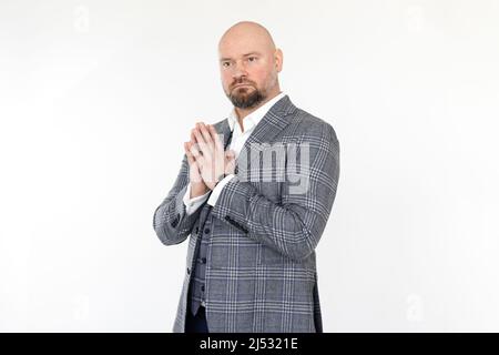 Portrait of confident middle-aged businessman wearing grey checkered jacket, vest, white shirt, standing, folding hands. Stock Photo