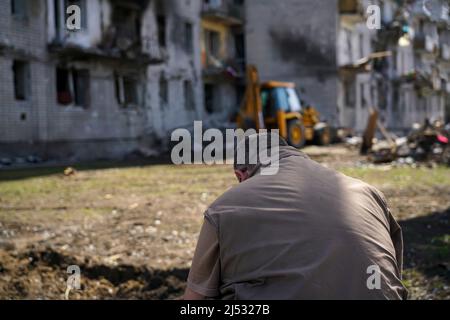 A man stands in front of the facade of a destroyed house during military operations in Ukarin Stock Photo