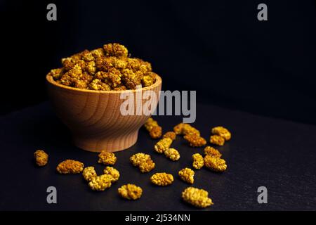 dried white mulberry fruit - latin Morus alba - in wooden bowl on black slate. Spices and food ingredients. Stock Photo
