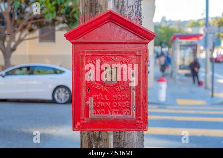 Fire alarm inside the small red house on a wooden post at crosswalk in San Francisco, California Stock Photo