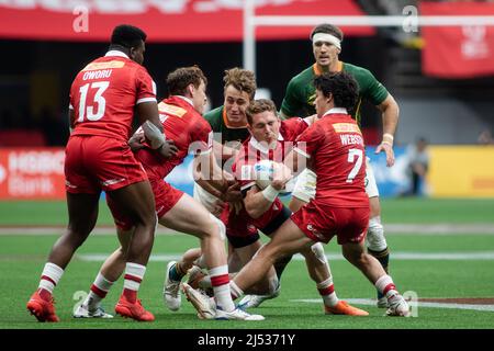 Vancouver, Canada, April 16, 2022: Cooper Coats (red, holding ball) and his teammates (red) in action against Team South African players (green) during day 1 of the HSBC Canada Sevens at BC Place in Vancouver, Canada. South Africa won the match with the score 19-14. Stock Photo