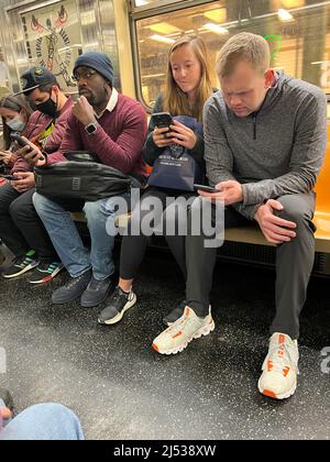 Subway riders glued to their phones as they ride a New York City subway train in New York City. Stock Photo
