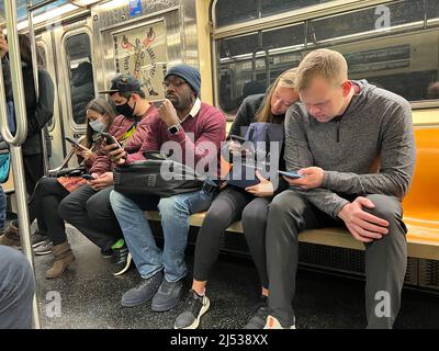 Subway riders glued to their phones as they ride a New York City subway train in New York City. Stock Photo