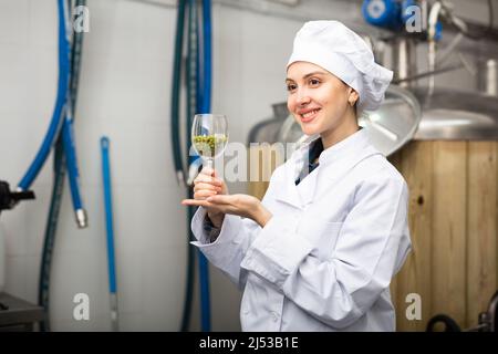 Successful female brewmaster showing hop pellets in glass Stock Photo