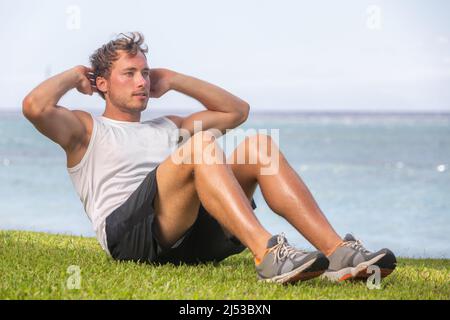 Fit man athlete training outside on grass doing situps for abs workout fat belly weight loss. Healthy active lifestyle Stock Photo