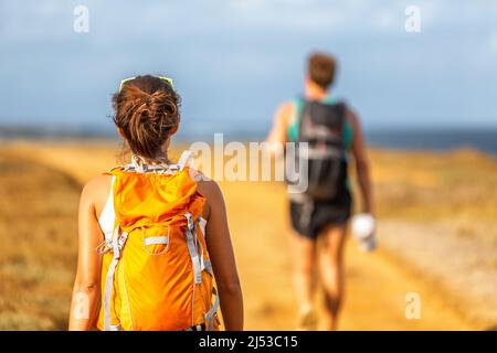 Hiking people couple walking with backpacks on hike trip trail in mountain nature outdoors. Tourists trek with bags Stock Photo