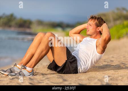 Fitness man doing abs crunches exercises workout fit outdoor on beach. Situps training stomach for fat weight loss male athlete working out Stock Photo