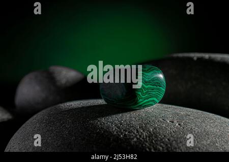 Malachite stone on a rock in the dark with a green light in the background, horizontal Macro Photography Stock Photo