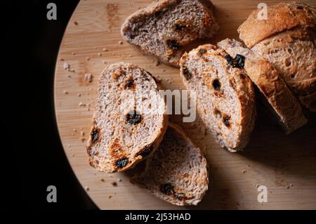 Slices of bread with raisins on a wooden cutting board close up top view, food photography Stock Photo