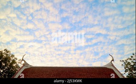 Amazing Altocumulus Clouds Lined Up on the Sky over Buddhist Temple Gable Roof Stock Photo