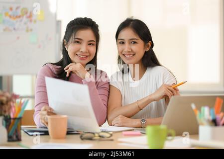 Portrait of a Happy and cheerful Asian young female college students sitting at their study table and smiling to camera. Stock Photo