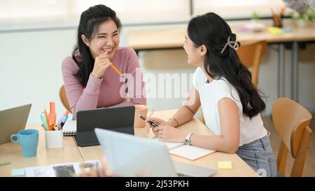 Attractive asian businesswoman and her colleague enjoy talking and having a good time together in the informal meeting. Stock Photo