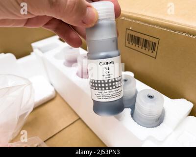 London, united Kingdom - Ap 3, 2022: Man hand unboxing Canon 53 gray color bottle of Canon PIXMA G550 single function printer with six refillable dye-based ink tanks, for high quality photo printing Stock Photo